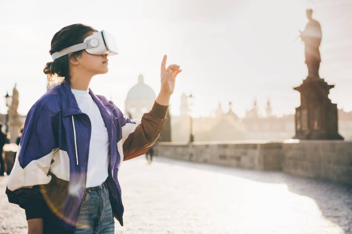 Woman wearing VR headset pointing outdoors on a sunny bridge with historical statues in the background.
