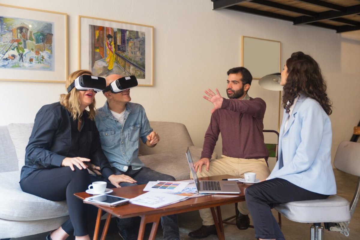 Four people using VR headsets during a meeting in a modern office, surrounded by colorful paintings.
