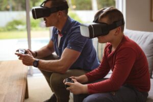 A man and a boy wearing VR headsets playing video games in a living room.