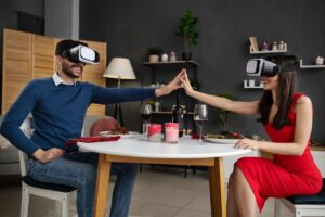 A man and a woman in VR headsets high-five over a romantic dinner setup.