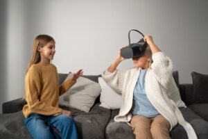 Young woman interacts with an older woman using a virtual reality headset on a couch.