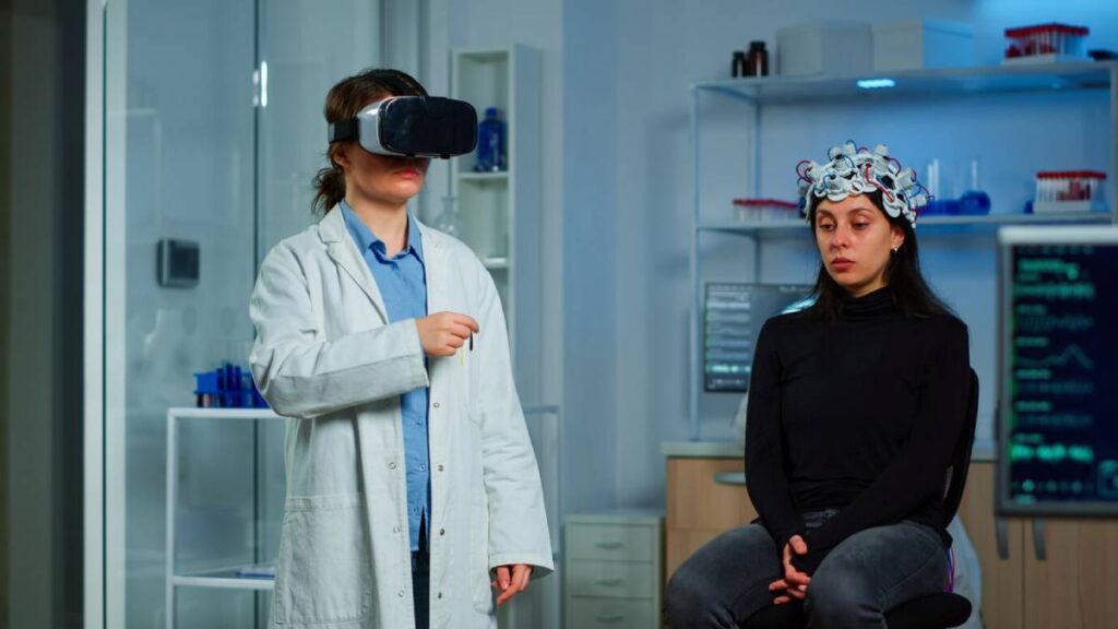 A scientist wearing VR goggles and a woman with a brainwave sensor cap sitting in a high-tech laboratory.