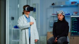 A scientist wearing VR goggles and a woman with a brainwave sensor cap sitting in a high-tech laboratory.